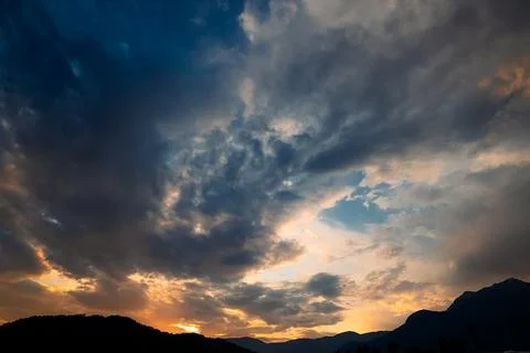 Clouds fill sky above  mountain range during sunset. colors change as dayligh Stock Photos