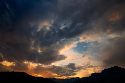 Clouds fill sky above  mountain range during sunset. colors change as dayligh Stock Photos