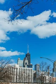 Clouds float above city buildings with a tall tower reaching into the sky d.. Fotos de archivo
