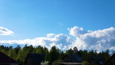 Clouds float above the forest and houses. Video stock 90738786
