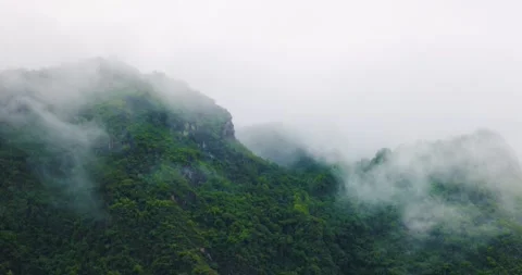 Clouds float above the green mountains covered with morning mist after the rain. Stock Footage 314692249