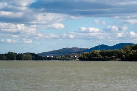 Clouds float above a river near hills with communication towers during the .. Stock Photos