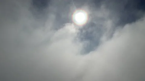 Clouds float across the blue sky in front of the sun Stock Footage 214762537