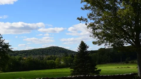 Clouds float over a meadow and mountain Stockbeeldmateriaal 139031284