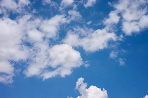 Clouds float in the sky above a rural setting. The blue sky stretches over th Stock Photos
