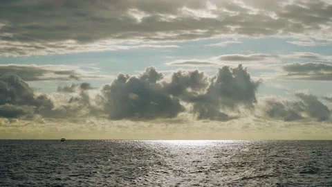 Clouds float at sunset over the sea and a small boat is also visible Stock Footage 168977349