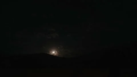 Clouds float through mountains against backdrop of night sky and moon. Video stock 218388645