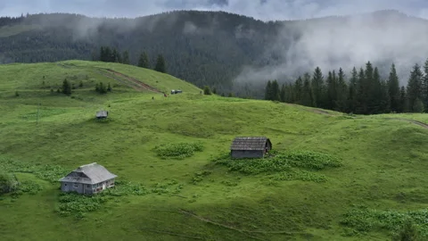 Clouds floating around mountain cottage village. Wild misty forest high on the Stock Footage 135321127