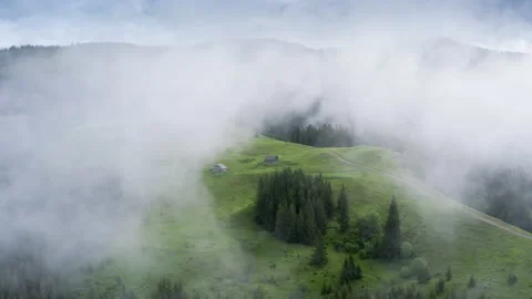 Clouds floating around mountain cottage village. Wild misty forest high on the Stock Footage 135321152