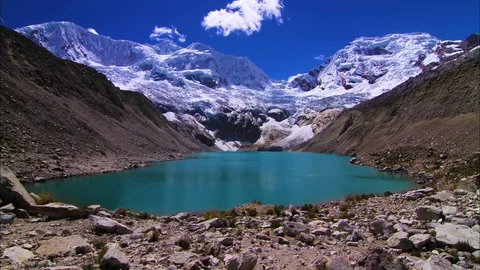 Clouds floating over green lake and snow covered mountain Stock Footage 77482851