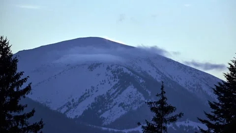 Clouds flow quickly over a snowy oval game at dusk . Shot from behind the trees Video stock 169596751