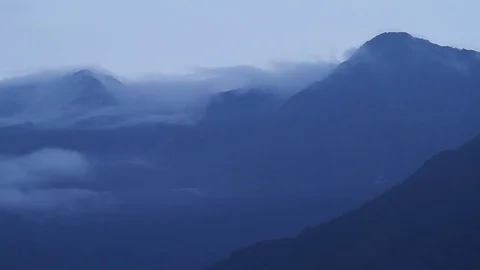 Clouds flowing gently behind mountains Stock Footage 116948588