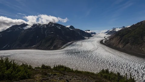 Clouds flowing over valley with receding glacier and lush green forest 8K time Stock Footage 114007134