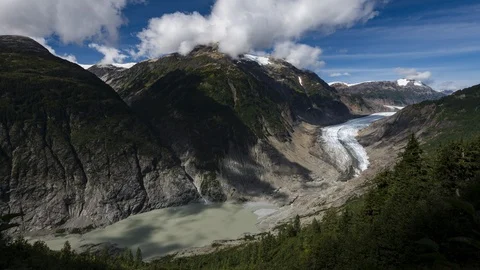 Clouds flowing over valley with receding glacier and lush green forest 8K time Stock Footage 114007920