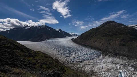 Clouds flowing over valley with receding glacier and lush green forest 8K time Stock Footage 114009175