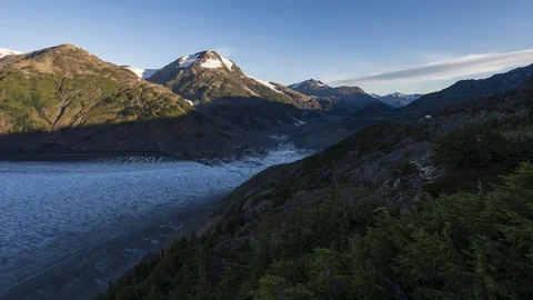 Clouds flowing over valley with receding glacier and lush green forest 8K time Stock Footage 114603752