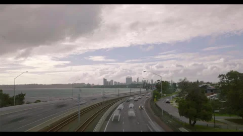 Clouds fly above city - traffic zooms along freeway beside river and railway Stock Footage 313184022