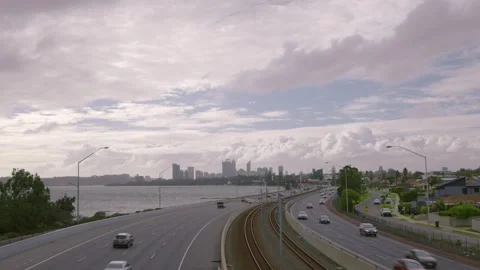 Clouds fly above city - traffic zooms along freeway beside river and, railway Stock-Footage 313184942