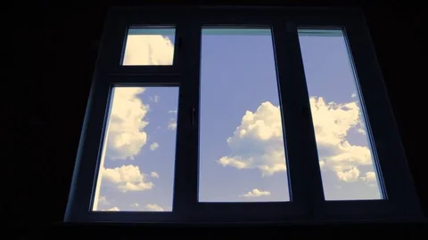 Clouds fly across a blue sky at the closed window. Timelapse. Stock Footage 76971552