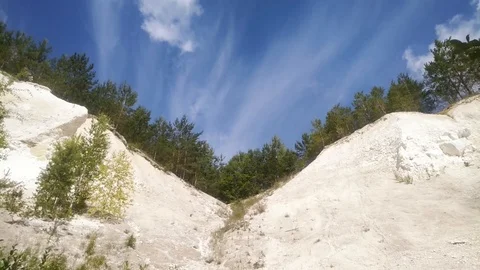 Clouds fly over the slopes of chalk quarries with trees on top, time lapse Stock Footage 125934502