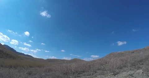 Clouds fly through the blue sky over the valley in the mountains Stock Footage 79384786