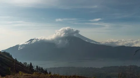 Clouds fly volcano Agung in front of him a lake, the grass stirs, forest Stock Footage 102055640