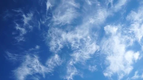 Clouds flying in a deep blue sky with mountains in background Stock Footage 76950827