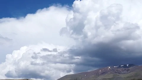 Clouds flying in a deep blue sky with mountains in background Stock Footage 76950829