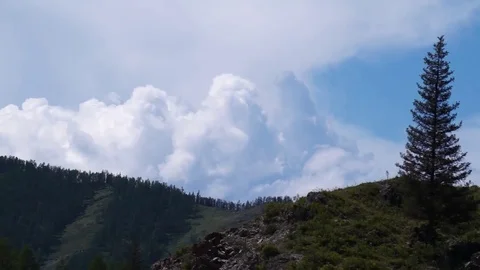 Clouds flying in a deep blue sky with mountains in background Stock Footage 76950844