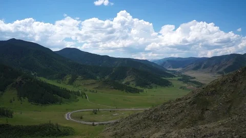 Clouds flying in a deep blue sky with mountains in background Stock Footage 76950847