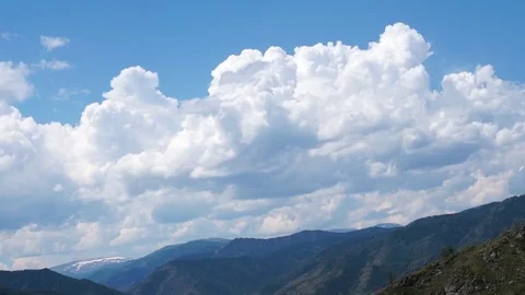 Clouds flying in a deep blue sky with mountains in background Stock-Footage 76950864