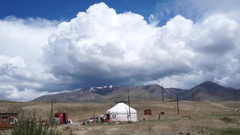 Clouds flying in a deep blue sky with mountains in background Stock Footage 76950870