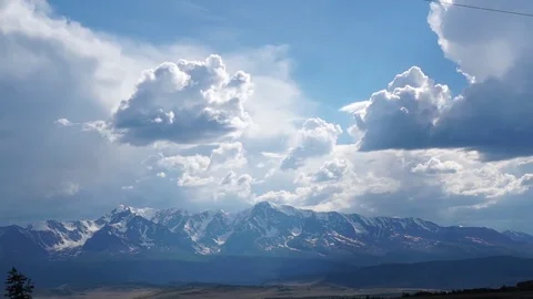 Clouds flying in a deep blue sky with mountains in background Stock Footage 76950890
