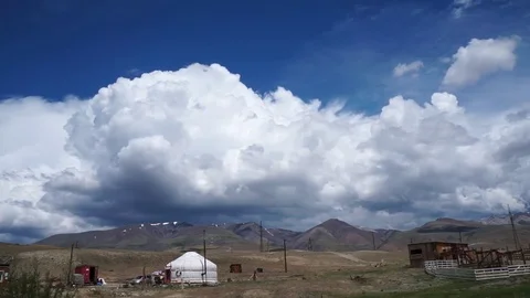 Clouds flying in a deep blue sky with mountains in background Stock Footage 76950891