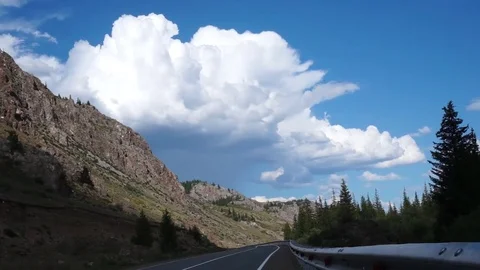 Clouds flying in a deep blue sky with mountains in background Stock Footage 76950901