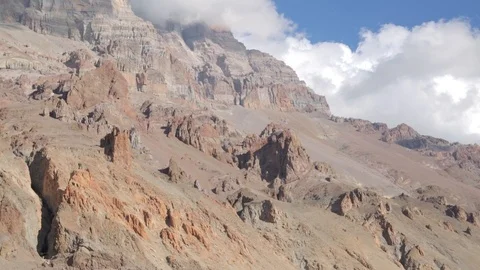 Clouds form over a rocky cliff face at Plaza De Mulas on Aconcagua Stock Footage 90877971
