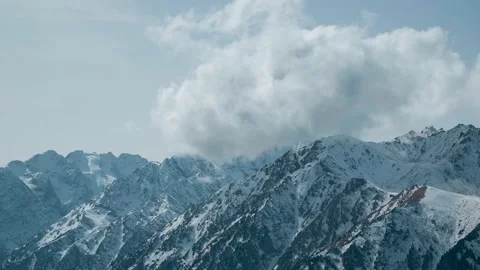 Clouds forming over rocky and snowy mountains Видео 231419960