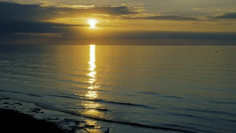 Clouds frame the setting summer sun on a calm sea Stock Footage 94617326