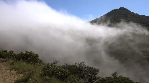 Clouds Funnelling Through Saddle in Mountain Ridge Stock Footage 74811767