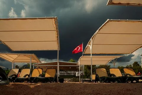 Clouds gather over beach area with sun loungers and Turkish flag flying in wi Foto stock