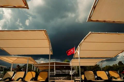 Clouds gather over beach area with sun loungers and Turkish flag flying in wi Stock-Fotos