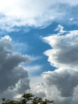 Clouds gather over a blue sky during the afternoon with a hint of sunlight .. Photos