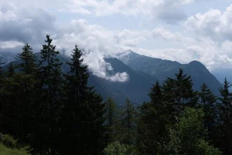 The clouds hanging in the mountains, trees in the front Stock Photos