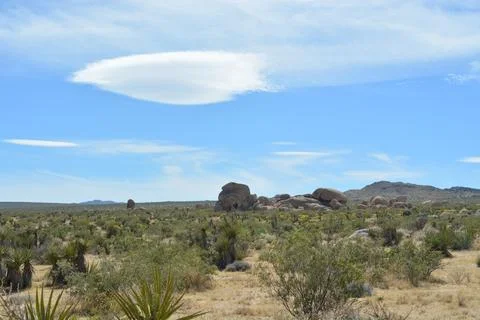 Clouds Hover Above Rugged Rocks in a Serene Desert Landscape Stock Photos