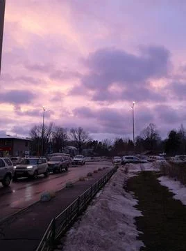 Clouds of lilac color illuminated by the rays of the setting sun over the city Foto stock