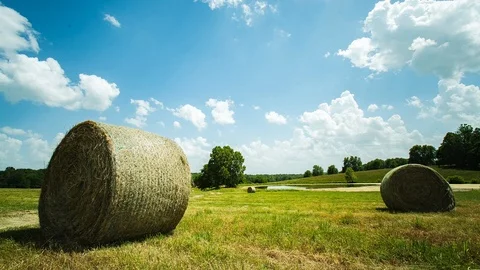 Clouds move above bales of hay Stock Footage