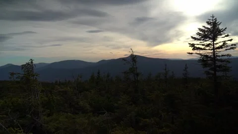 Clouds move over mountains at sunset near forest clearings Stockbeeldmateriaal 330120746