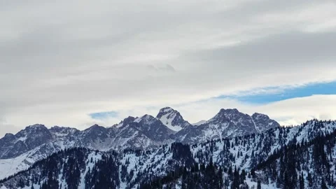 Clouds move over the tops of snow-capped mountains Stock Footage 144535194