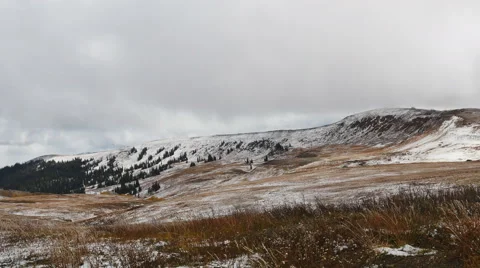 Clouds move rapidly over snowy mountain brown grass blowing foreground Stock Footage 68544375