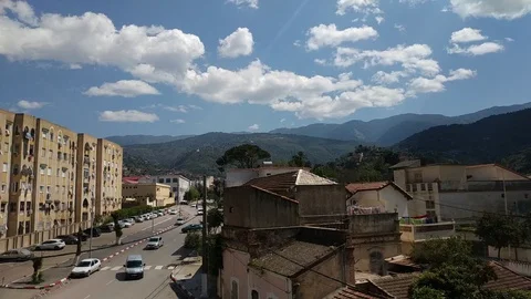The clouds movement over mountains with car movement and people (IN TOWN CENTER) Stock Footage